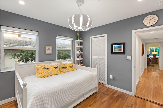 bedroom featuring wood-type flooring, a chandelier, and a closet