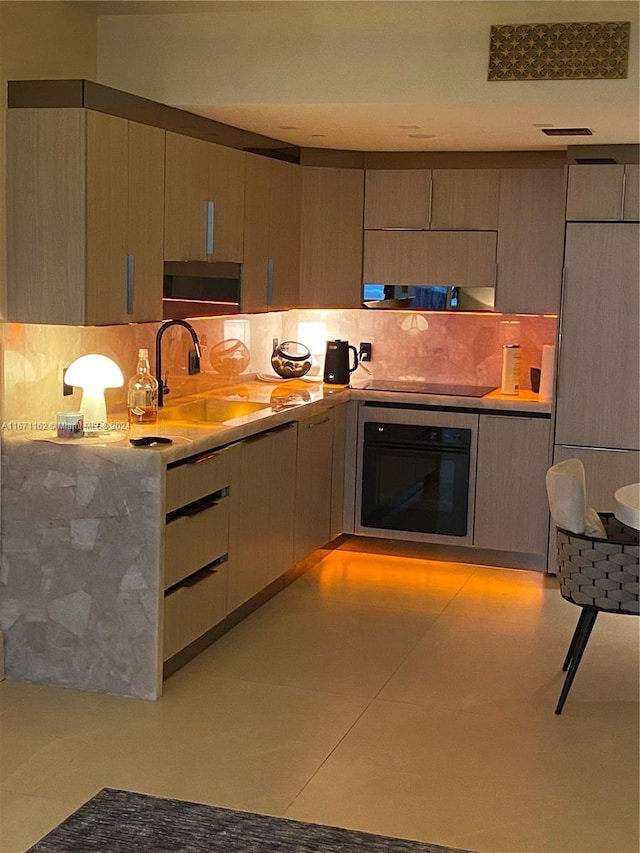 kitchen with black appliances, sink, light tile patterned floors, and backsplash