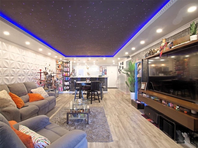 living room featuring a raised ceiling, light wood-type flooring, and ornamental molding