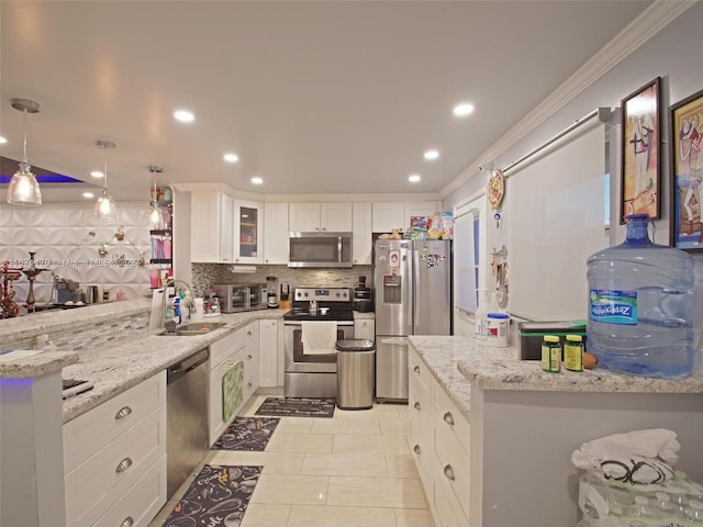 kitchen featuring hanging light fixtures, ornamental molding, stainless steel appliances, and white cabinets