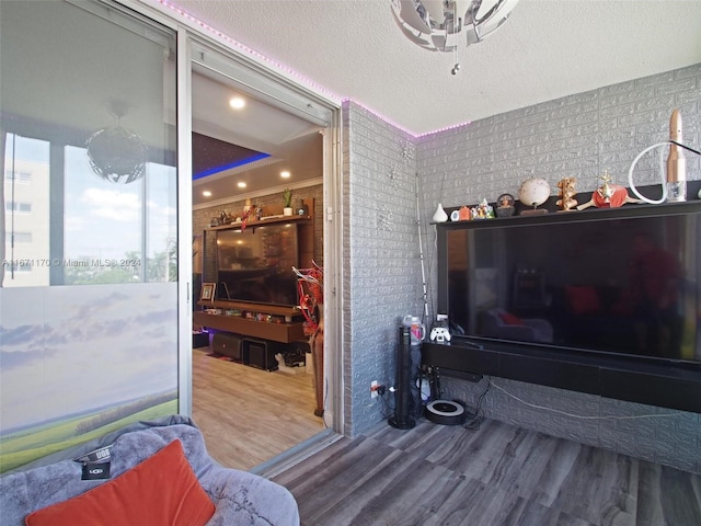 living room featuring wood-type flooring, a textured ceiling, and ornamental molding