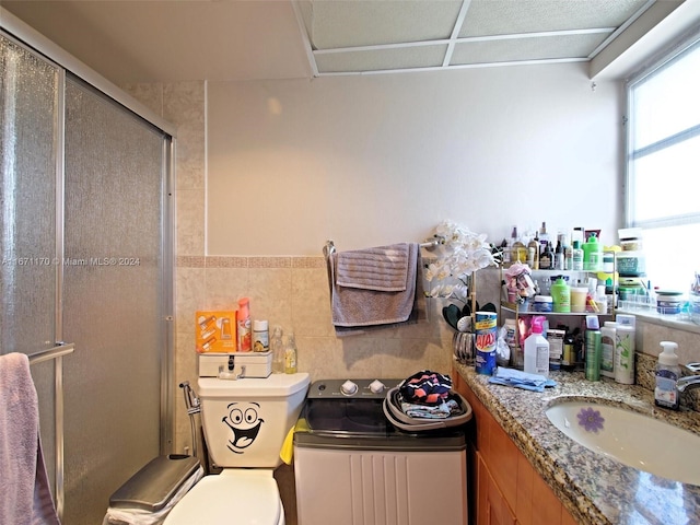 bathroom featuring walk in shower, vanity, tile walls, and toilet