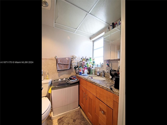 bathroom featuring vanity, a drop ceiling, and toilet