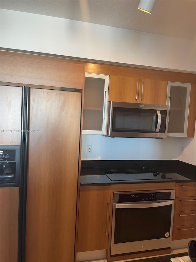 kitchen with appliances with stainless steel finishes and dark stone counters