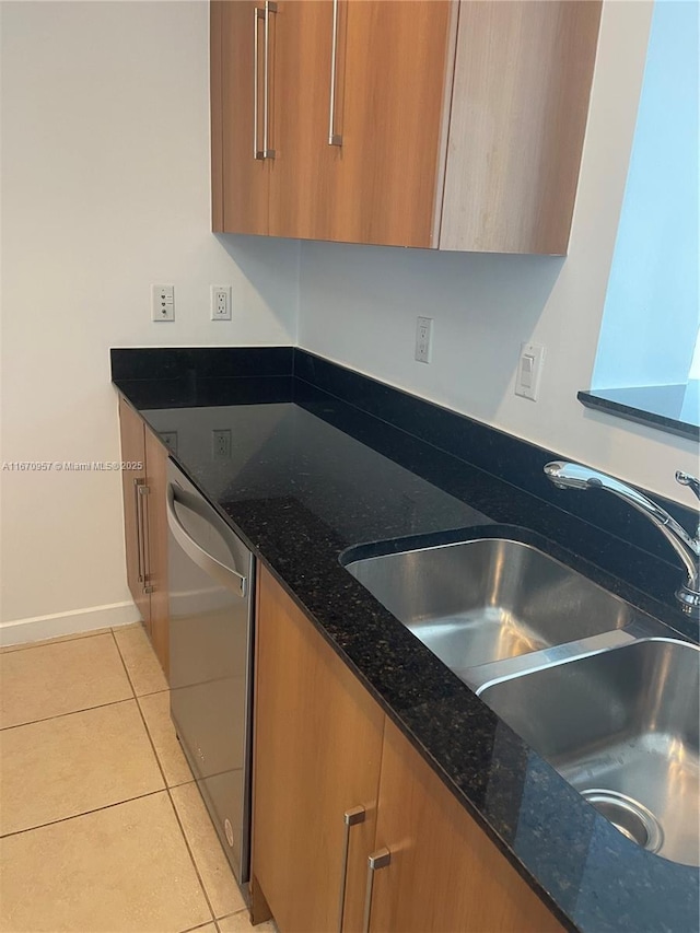 kitchen with dishwasher, dark stone countertops, light tile patterned floors, and sink