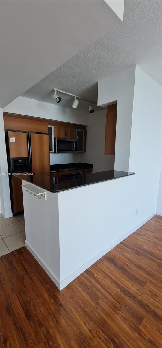 kitchen featuring hardwood / wood-style floors, refrigerator with ice dispenser, and a textured ceiling