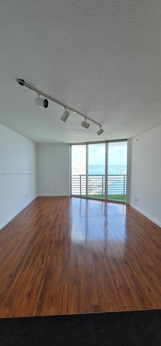 spare room featuring a textured ceiling, track lighting, and hardwood / wood-style flooring