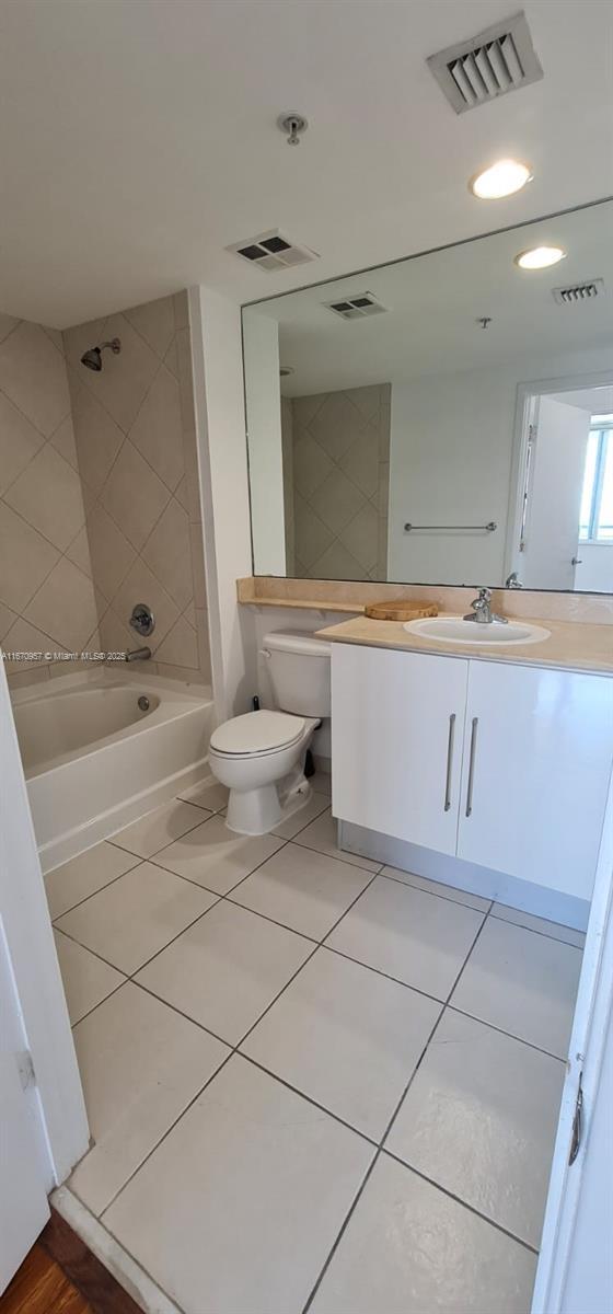 full bathroom featuring tile patterned flooring, vanity, tiled shower / bath combo, and toilet