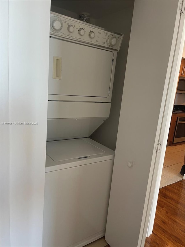 laundry area featuring wood-type flooring and stacked washer and clothes dryer