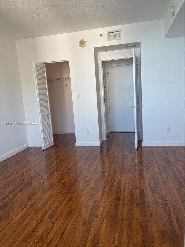 unfurnished bedroom featuring a textured ceiling and dark hardwood / wood-style flooring