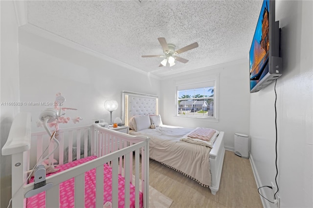 bedroom with ceiling fan, light wood-type flooring, a textured ceiling, and ornamental molding