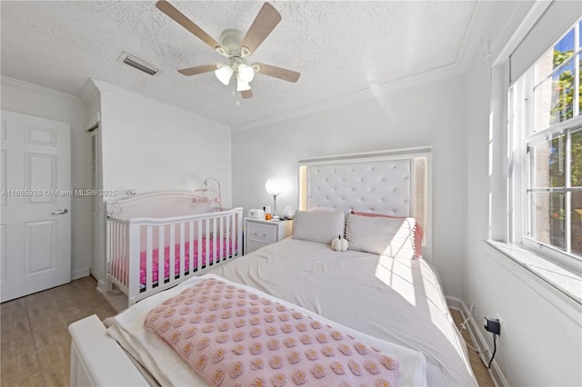 bedroom with ceiling fan, light hardwood / wood-style floors, a textured ceiling, and multiple windows