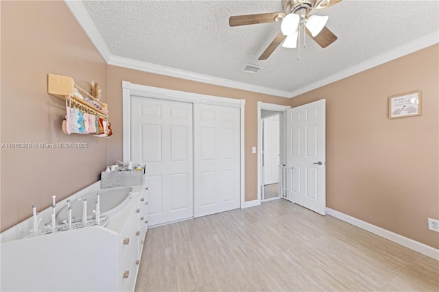 bedroom with ceiling fan, crown molding, light hardwood / wood-style floors, a textured ceiling, and a closet