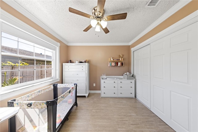 bedroom featuring ceiling fan, a closet, crown molding, and a textured ceiling