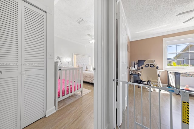 hall with light tile patterned floors, a textured ceiling, and crown molding