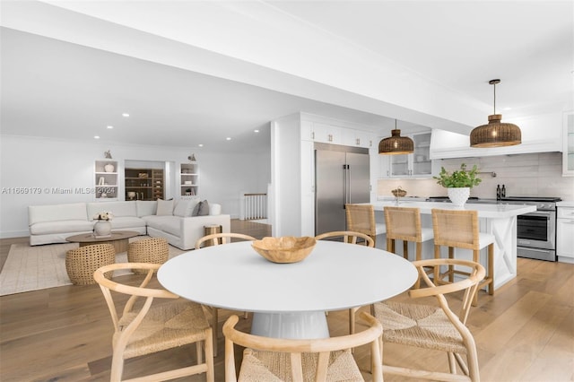 dining space with light wood-type flooring and crown molding