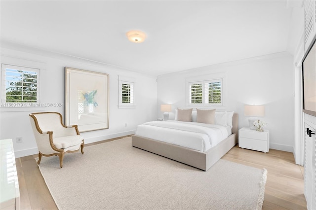 bedroom with light hardwood / wood-style flooring, multiple windows, and crown molding