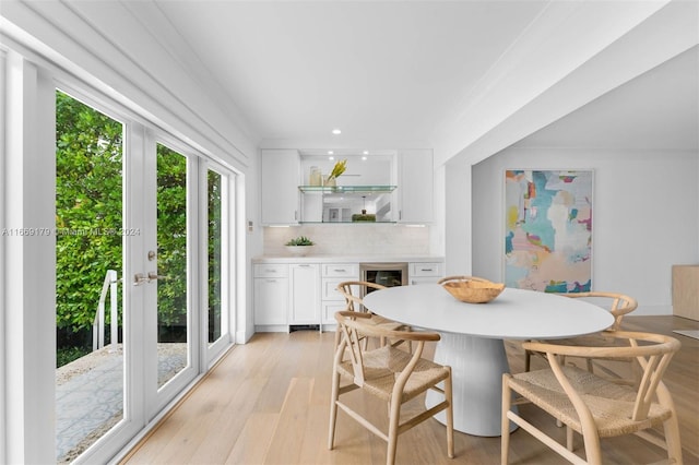 dining space featuring light hardwood / wood-style flooring, wine cooler, and ornamental molding