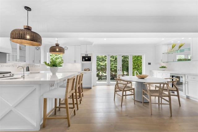 interior space with french doors, wine cooler, light wood-type flooring, and sink