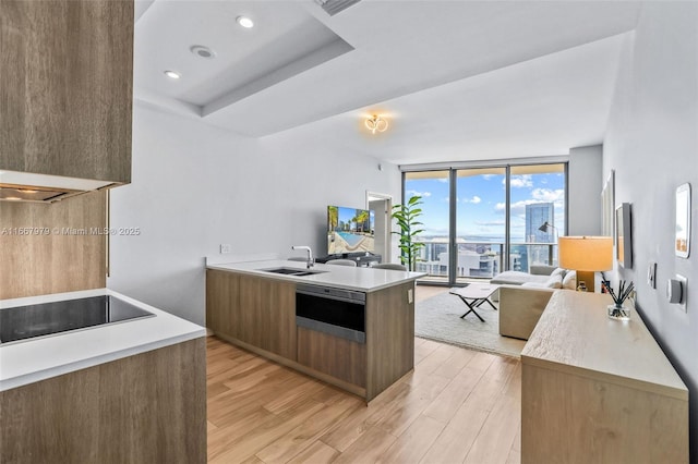 kitchen with kitchen peninsula, black electric cooktop, floor to ceiling windows, light hardwood / wood-style flooring, and sink