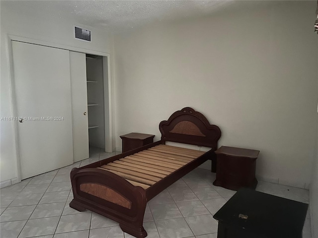 bedroom with a textured ceiling, a closet, and light tile patterned floors