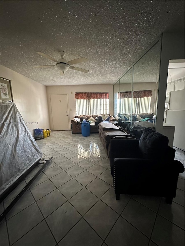 living room featuring ceiling fan, a textured ceiling, and tile patterned flooring