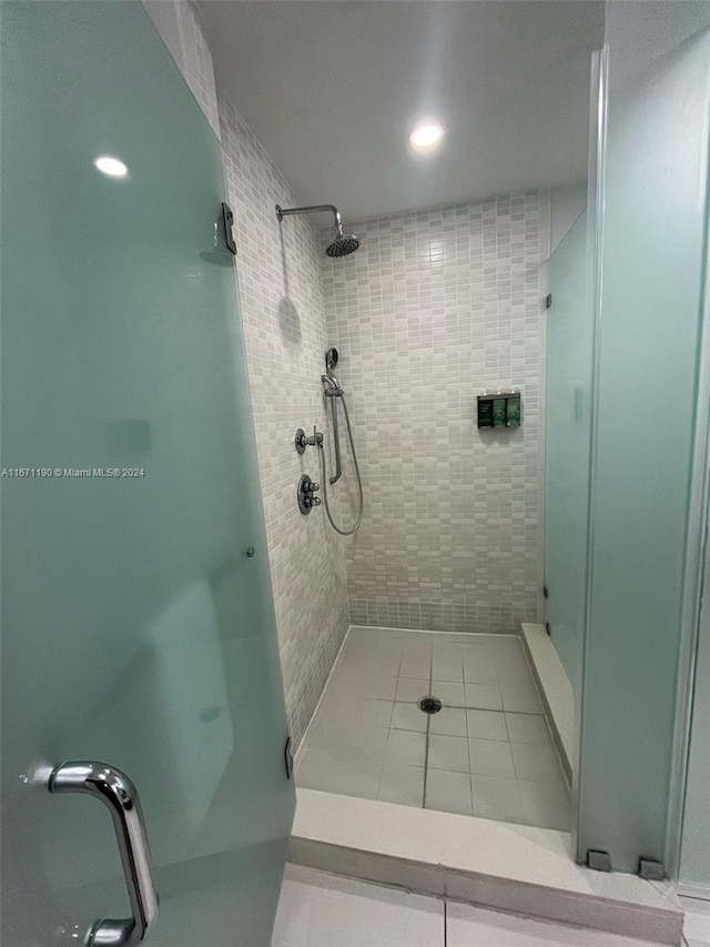 bathroom with a shower with door and tile patterned floors