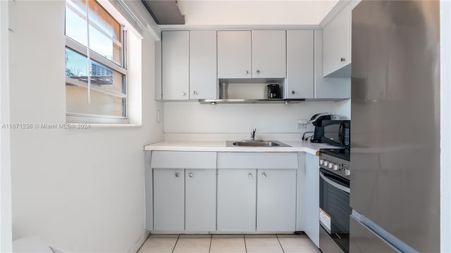 kitchen featuring light tile patterned floors, appliances with stainless steel finishes, sink, and white cabinetry