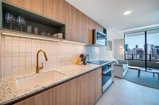 kitchen with sink, stainless steel appliances, backsplash, light tile patterned floors, and light stone countertops