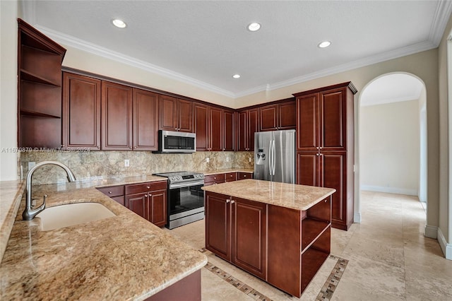 kitchen with a center island, decorative backsplash, sink, light stone countertops, and appliances with stainless steel finishes