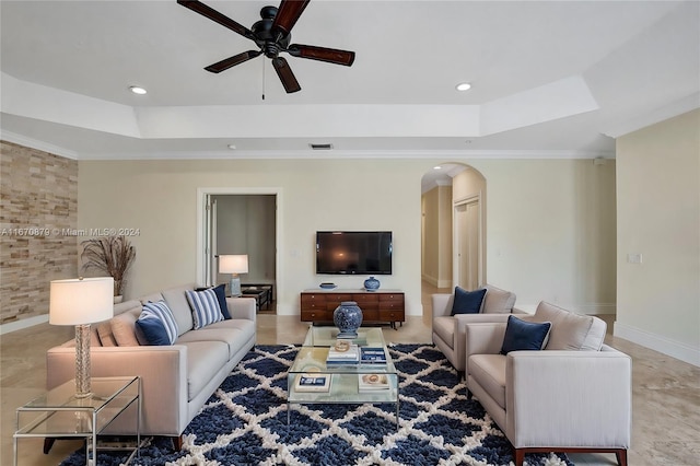 living room with ceiling fan, a raised ceiling, and crown molding