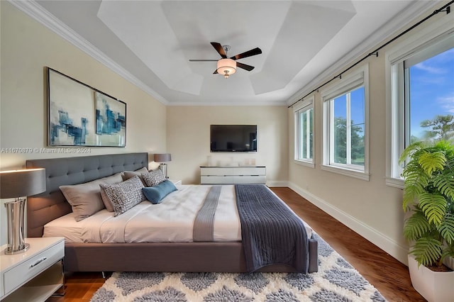 bedroom with ceiling fan, dark hardwood / wood-style floors, a raised ceiling, and crown molding