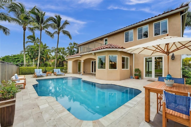 back of property featuring a balcony, a fenced in pool, and a patio area