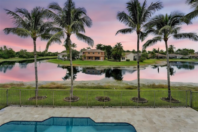 pool at dusk with a lawn and a water view