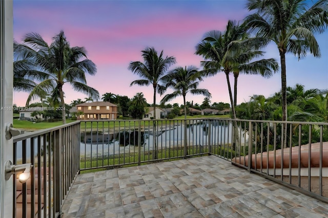 patio terrace at dusk with a water view and a balcony