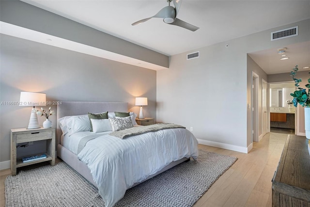 bedroom with ceiling fan, connected bathroom, and light hardwood / wood-style floors