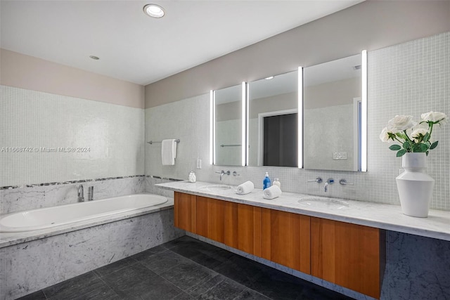 bathroom featuring a relaxing tiled tub, tile walls, tile patterned flooring, and vanity