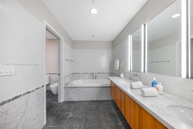 bathroom with tile walls, vanity, a relaxing tiled tub, toilet, and a bidet