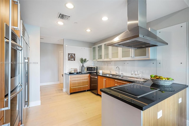 kitchen featuring light hardwood / wood-style floors, sink, kitchen peninsula, island range hood, and black appliances