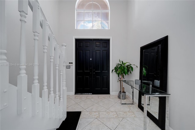 entryway with light tile patterned flooring and a high ceiling