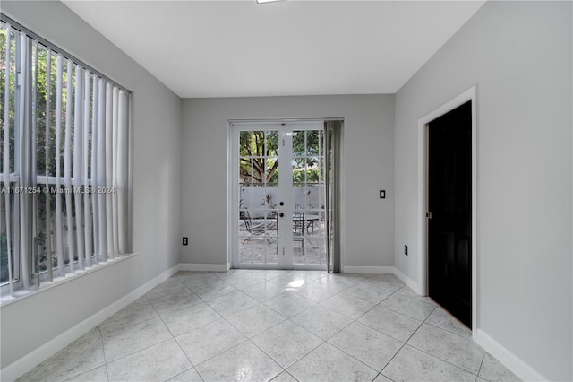 tiled empty room featuring french doors