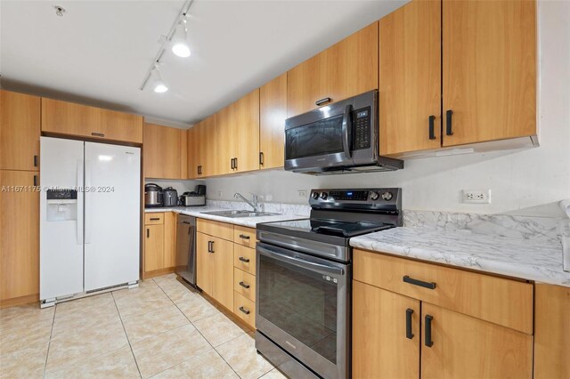 kitchen with rail lighting, appliances with stainless steel finishes, light tile patterned flooring, and sink