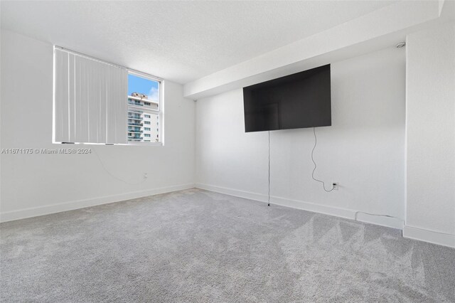 carpeted empty room with a textured ceiling