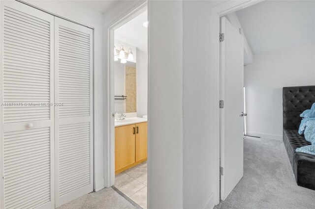 hallway with light carpet and sink