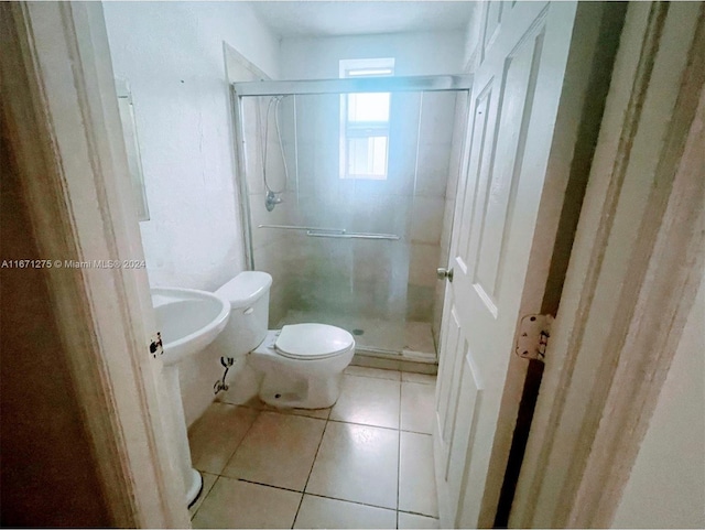 bathroom featuring a shower with shower door, toilet, and tile patterned floors