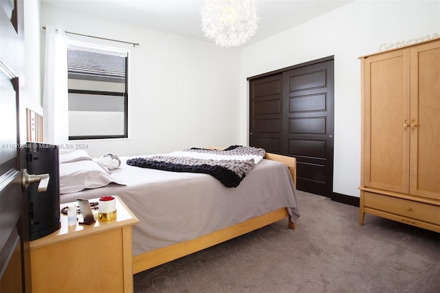 bedroom with dark colored carpet and a chandelier