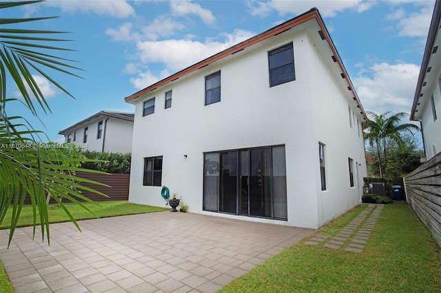 back of property with a lawn and a patio