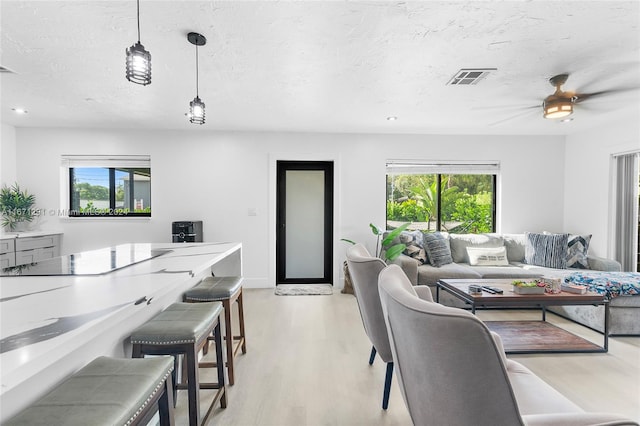 living room with a textured ceiling, light hardwood / wood-style floors, ceiling fan, and a wealth of natural light