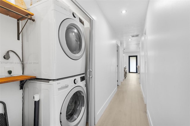 laundry room with light hardwood / wood-style flooring and stacked washer / drying machine