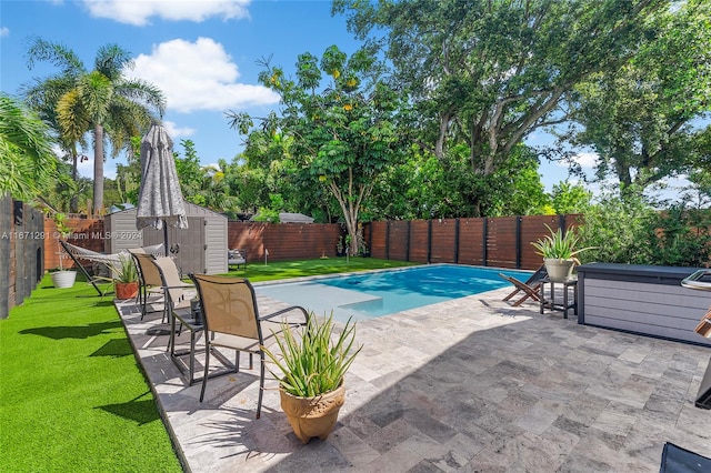 view of pool with a storage unit, a patio area, and a yard